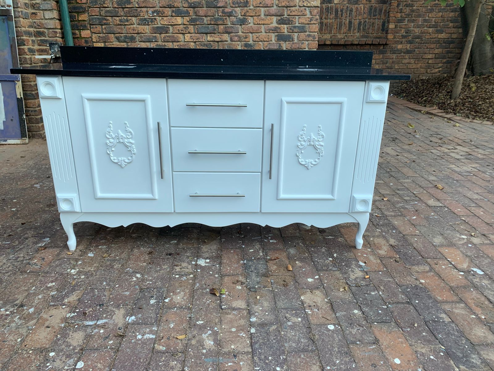 White double vanity, black galaxy top, embellished doors and silver/black bar handles.